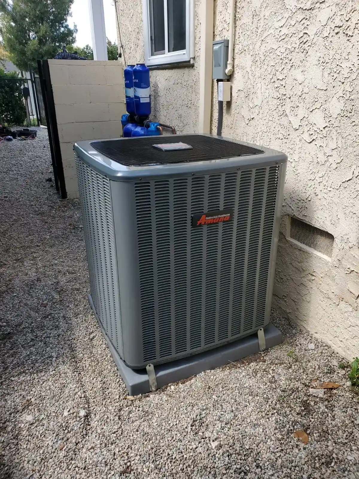 New air conditioning condenser on a gravel pad beside a home