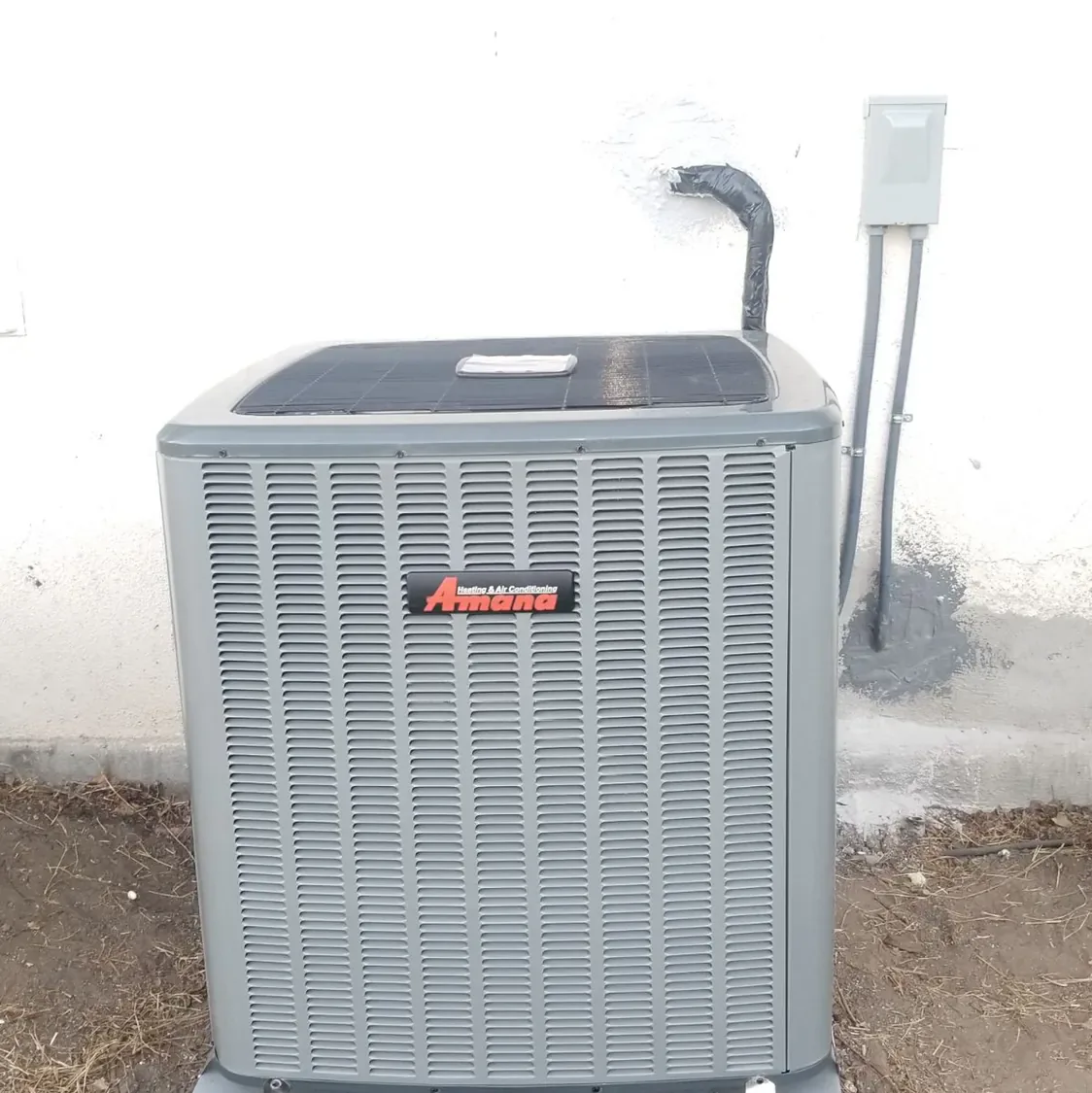 New air conditioning condenser installed against a white wall