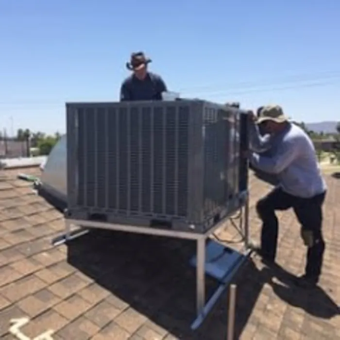 Two technicians installing a rooftop package unit