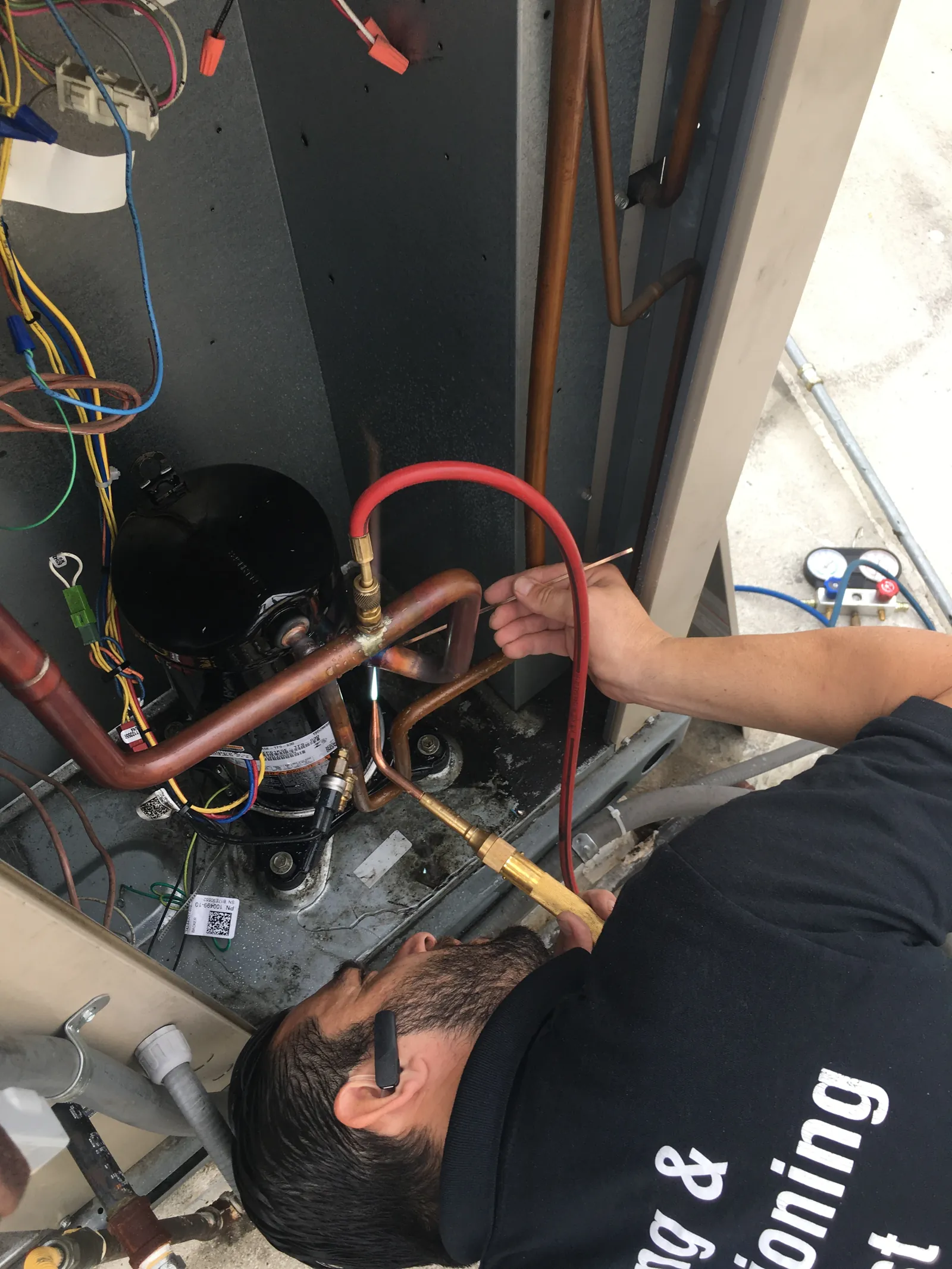 Technician working on the refrigerant lines of an air conditioner