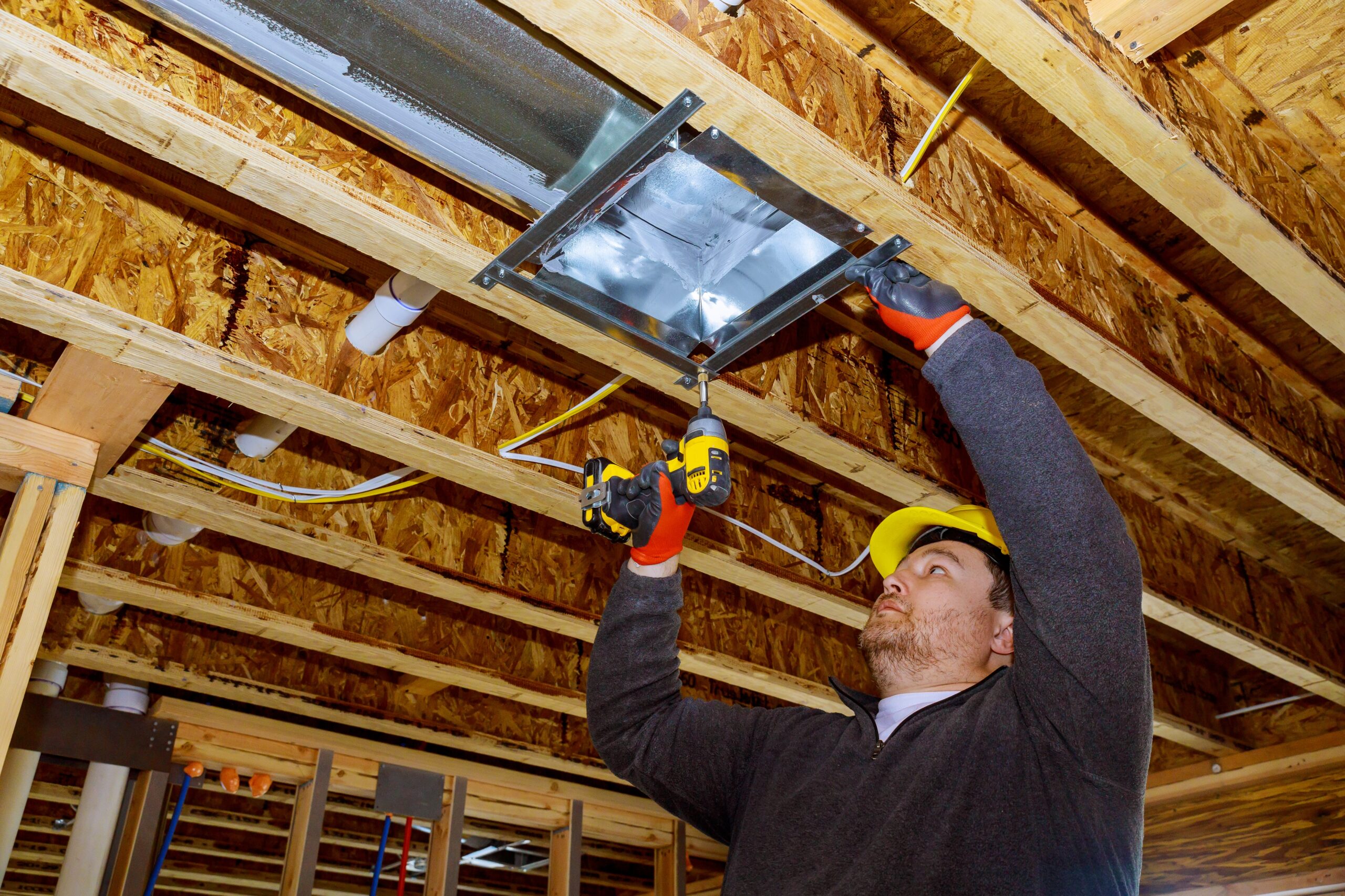 male technician mounted air conditioner on ceiling ventilation system
