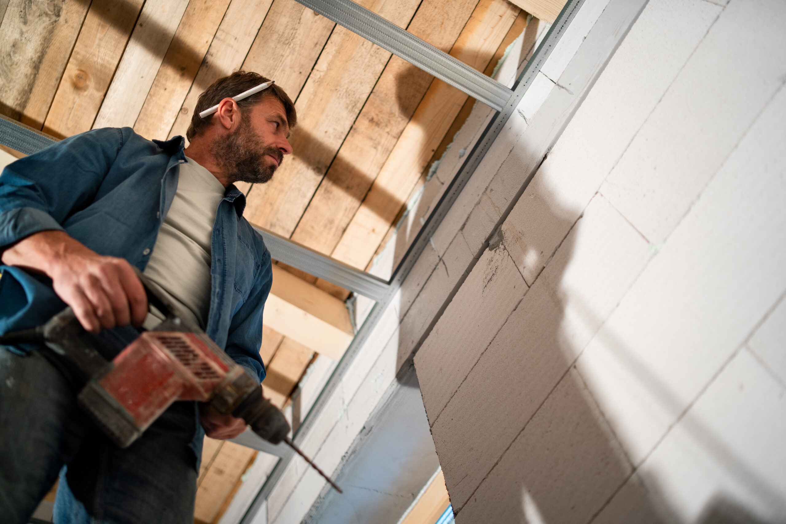 low angle view of handyman working with drill on construction site.