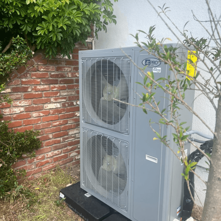 Large heat pump condenser installed beside a brick wall